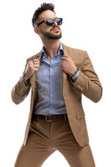 Wall Mural - cool fashion man with sunglasses pulling and arranging suit