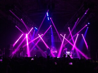 Pink and blue lights above the stage. Laser show at a live performance. Gig, concert. Strobe lights. Stage, scene. Perform. Live show. Purple rays. Spotlight. Festival. Violet gradient. Band. Fans