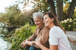 © Westend61 - Cheerful woman sitting with senior man by lake