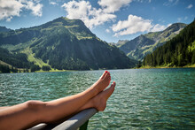 Woman's Legs On Prow Of Rowboat In Lake