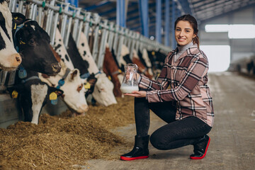 Young woman standing with milk jug at the cowshed