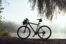 Silhouette Of Parked Bicycle Near River Shore In The Autumn Morning Haze