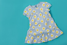 Light Blue Baby Dress With Yellow Flowers, On A Turquoise Background, Summer Concept