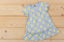 Light Blue Baby Dress With Yellow Flowers, On Wooden Boards, Summer Concept