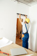 © Kostiantyn - Busy handyman, male worker in uniform checking the wall with spirit level