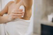 © Petro - Woman using deodorant at her bathroom wearing bath towel