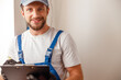 © Kostiantyn - Portrait of electrical technician in uniform smiling at camera, writing the data collected on a residential electric panel