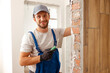 © Kostiantyn - Portrait of hard working handyman or craftsman smiling at camera while filling the wall, preparing it for painting