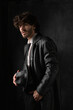 © horimono - Young man with beard in white shirt and black leather coat with hat against black background. High quality photo