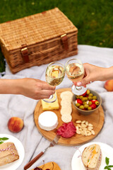 Wall Mural - leisure, food and drinks concept - close up of hands hands clinking wine glasses above picnic blanket at summer park