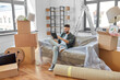 © Syda Productions - moving, people and real estate concept - happy smiling man with tablet pc computer and boxes at new home