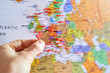 canvas print picture - Eine Hand setzt gerade eine Pin Markierung auf eine Landkarte, Ausschnitt liegt auf Europa - Reise, Weltreise