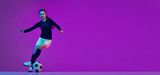 Fototapeta Londyn - Professional female soccer player dribbling football ball isolated on purple studio background in neon light. Sport, action, motion, fitness