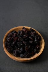 Wall Mural - raisins in a wooden bowl on black stone surface