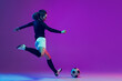 © master1305 - Dynamic portrait of female soccer player practicing with football ball isolated on purple studio background in neon light. Sport, action, motion, fitness