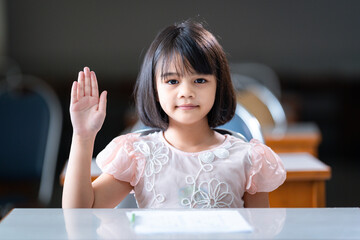 Sticker - A female Asian kid student raising a hand to ask teacher question in the classroom