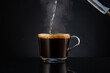 pouring boiling water into coffee in a transparent glass empty mug on a dark background