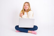© Jihan - People, lifestyle, youth and happiness concept. Shy pretty caucasian teen girl sitting with laptop in lotus position on white background , feeling happy hugging herself.