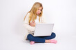 © Jihan - caucasian teen girl sitting with laptop in lotus position on white background suffering from strong stomachache.