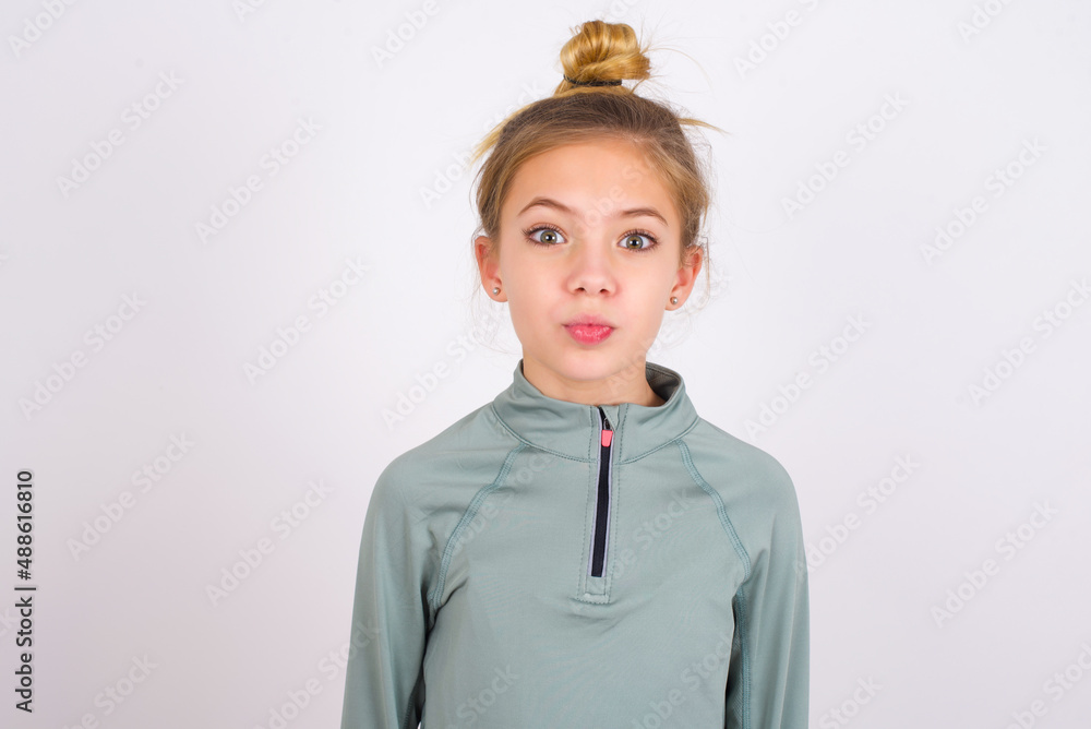Shot of pleasant looking little caucasian kid girl with hair bun ...