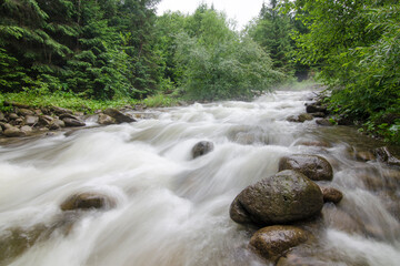 Stormy stream of a mountain river. Silky water surface, long exposure.