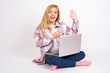© Jihan - I swear, promise you not regret. Portrait of sincere caucasian teen girl sitting with laptop in lotus position on white background raising one arm and hold hand on heart as give oath,