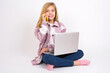 © Jihan - Portrait of a smiling  caucasian teen girl sitting with laptop in lotus position on white background talking on mobile phone. Business, confidence and communication concept.