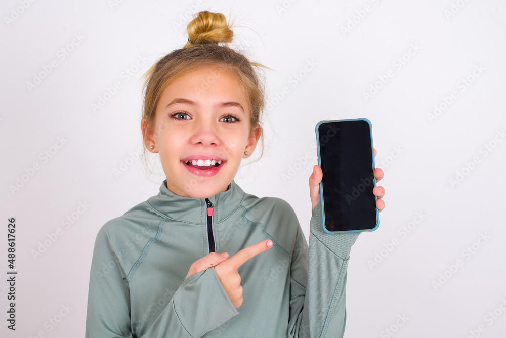 Attractive cheerful little caucasian kid girl with hair bun wearing ...