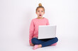 © Jihan - Shocked caucasian teen girl sitting with laptop in lotus position on white background stares bugged eyes keeps mouth opened has surprised expression. Omg concept