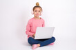 © Jihan - Displeased Beautiful caucasian teen girl sitting with laptop in lotus position on white background frowns face feels unhappy has some problems. Negative emotions and feelings concept