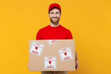 Professional Fun Delivery Guy Employee Man In Red Cap T-shirt Uniform Workwear Work As Dealer Courier Hold Cardboard Box With Fragile Text Isolated On Plain Yellow Background Studio. Service Concept.