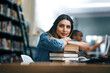 © Jadon Bester/peopleimages.com - Where dreams are turned into reality. Shot of a young woman resting on a pile of books in a college library and looking thoughtful.
