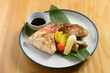 japanese cuisine hamachi kama with lemon, tomato, ginger and sauce in a plate isolated on wooden table top view