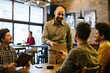 © Drazen - Happy waiter gives menu to group of young men while serving them in pub.