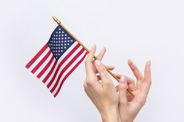 A beautiful female hand holds an American flag on a white background.