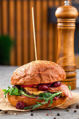 Wall Mural - Creative craft burger with fried slices of bacon and cherry, fresh arugula. Street food concept.