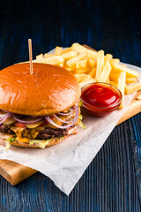 Wall Mural - large burger with potatoes and ketchup close-up, big burger and some french fries