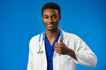 Wall Mural - Young african american man wearing doctor uniform and stethoscope in blue studio