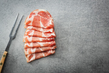 Poster - Italian dried ham. Coppa Stagionata with fork on kitchen table.