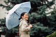 Young happy Asian businesswoman with an umbrella walking in the city.