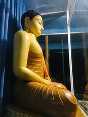 Poster - Vertical of the Buddha statue sitting against a blue curtain