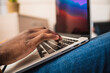 © Cavan Images - Close up of black man's hands typing on laptop in an office.