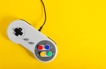 Photo Of Classic Gray Colored 8 Bit Game Pad Controller Laying On Yellow Background.
