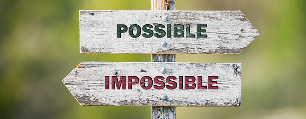 Wall Mural - opposite signs on wooden signpost with the text quote possible impossible engraved. Web banner format.