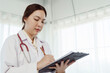 © Ekkasit A Siam - 4k, Asian female doctor Wearing a white dress is standing to write down patient information in the hospital.