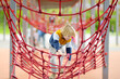 Cute perky preschooler boy having fun on outdoor playground. Spring or summer or autumn active sport leisure for kids. Modern equipment for outdoor children park of entertainments