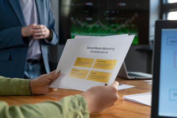Poster - Hands of young businesswoman holding papers with marketing considerations while looking through information