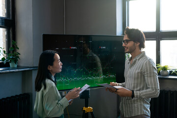 Aufkleber - Two young confident analysts with documents discussing interactive financial data while businessman explaining something to female colleague
