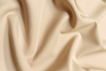 Golden crumpled or wavy fabric texture background. Abstract linen cloth soft waves. Silk atlas or stretch jacquard. Smooth elegant luxury cloth texture. Concept for banner or advertisement.