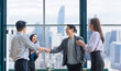 Asian business team leader congratulate his teammate employee for the outstanding achievement team performance by shaking hand in the modern office workplace with skyscraper view